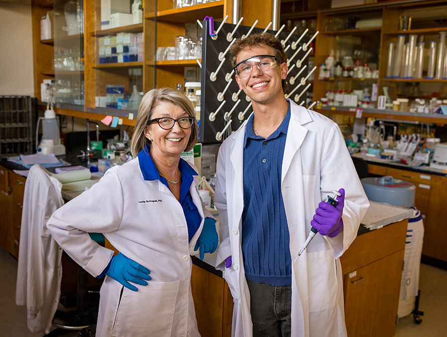 Lucia Notterpek, Ph.D., and Boston Boyack in white coats in a laboratory space. 