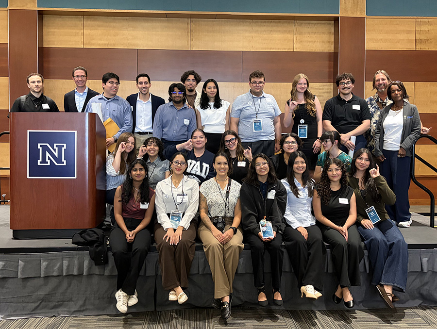 Group of students and faculty from Nevada State University pose for a photo on a state.