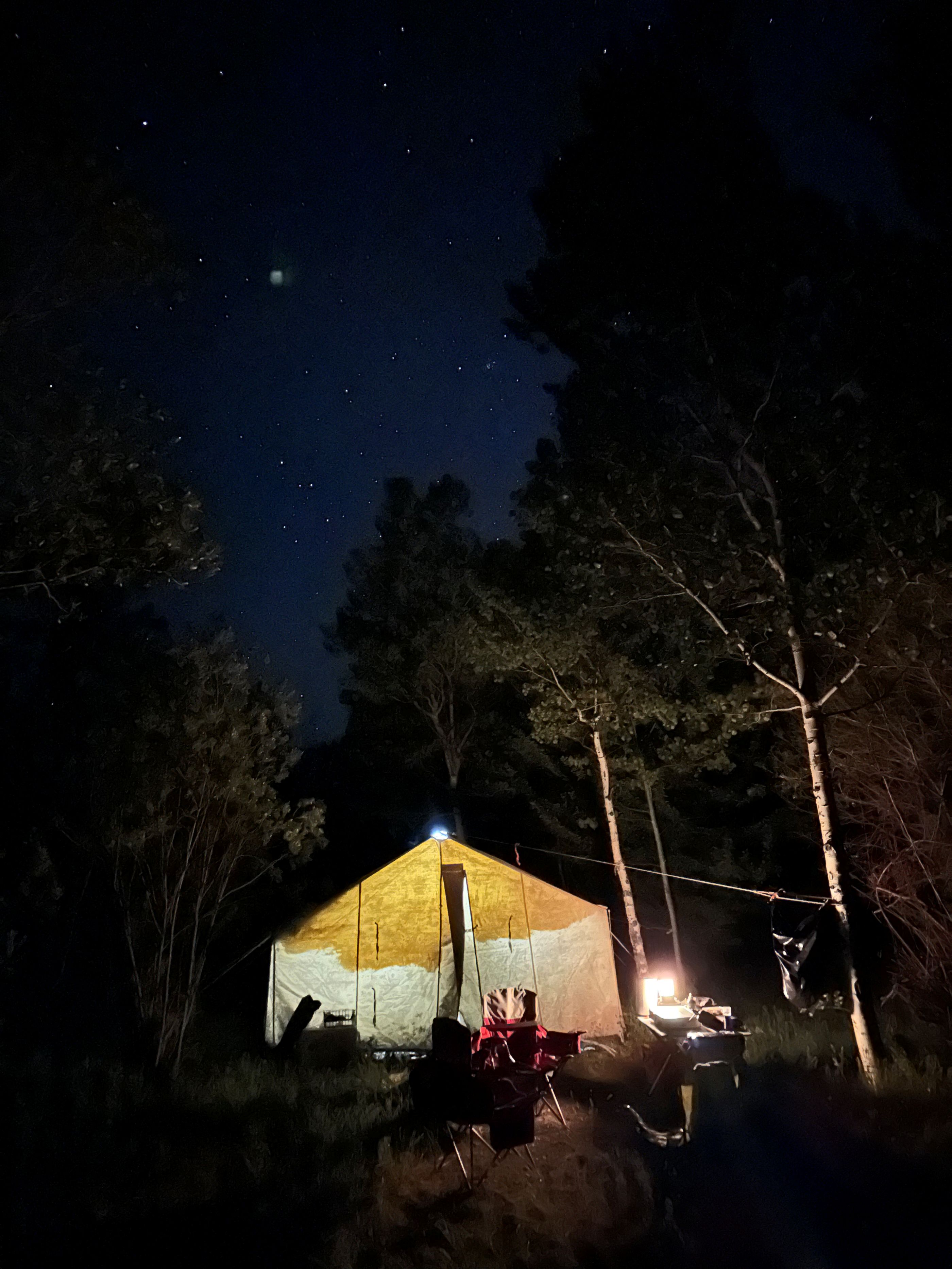A lit camping tent on a starry night. 