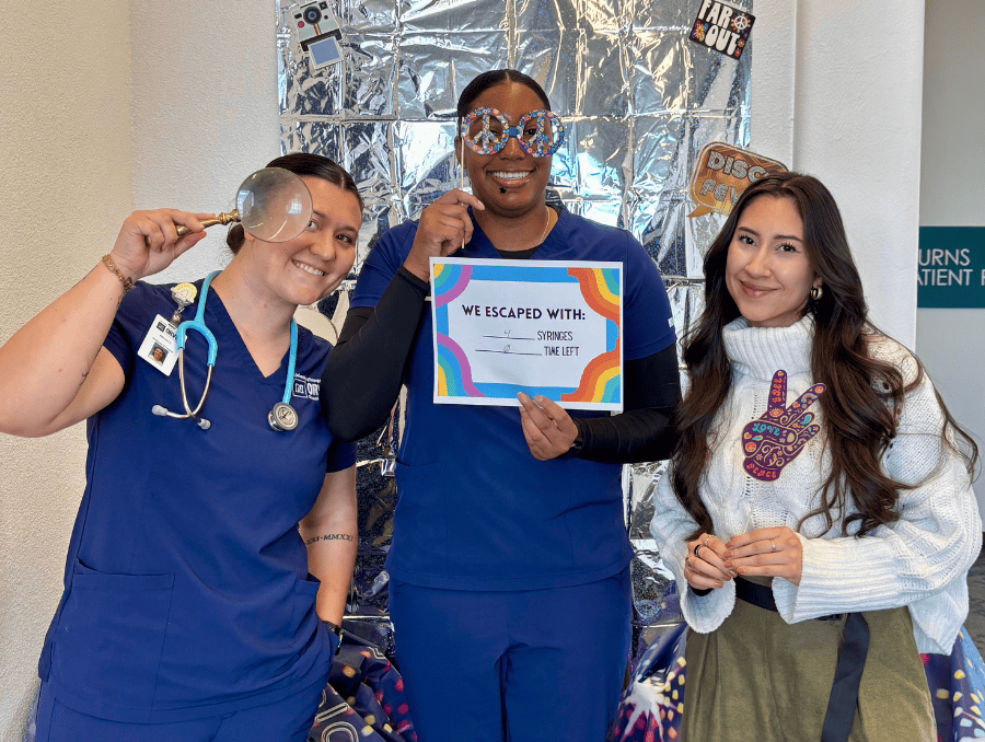 Three women are posing with props and a certificate of completion.