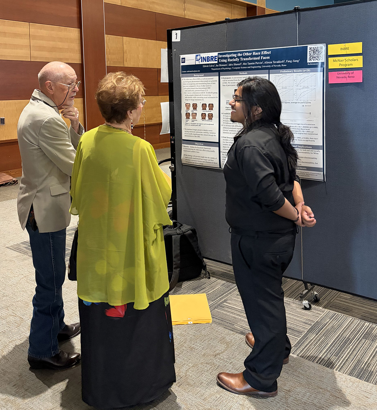 Wolf Pack Discoveries student presents a research poster to two event attendees.