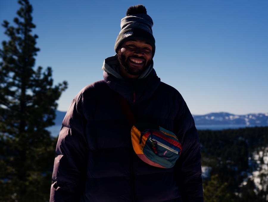 Deandre Presswood smiles on top of a snowy mountain.