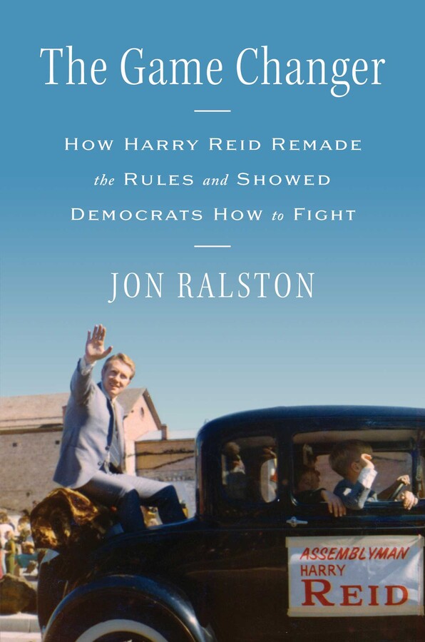 Book cover showing a young Harry Reid sitting in the back of a classic car waving to fans in a crowd. He appears to be riding in a parade. The classic car has a hand-made sign on the passenger-side door with a white background that reads in red letters &ldquo;Assemblyman Harry Reid.&rdquo; The cover reads: "The Game Changer; how Harry Reid remade the rules and showed democrats how to fight; Jon Ralston"