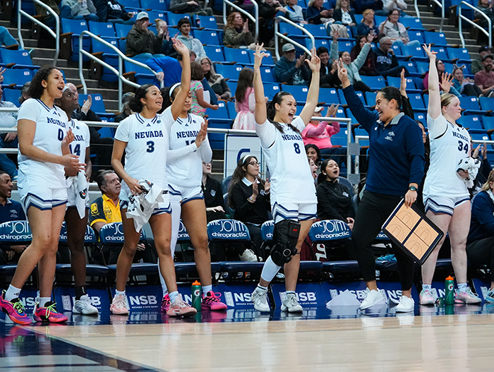 Nevada women's basketball players celebrate from the bench.