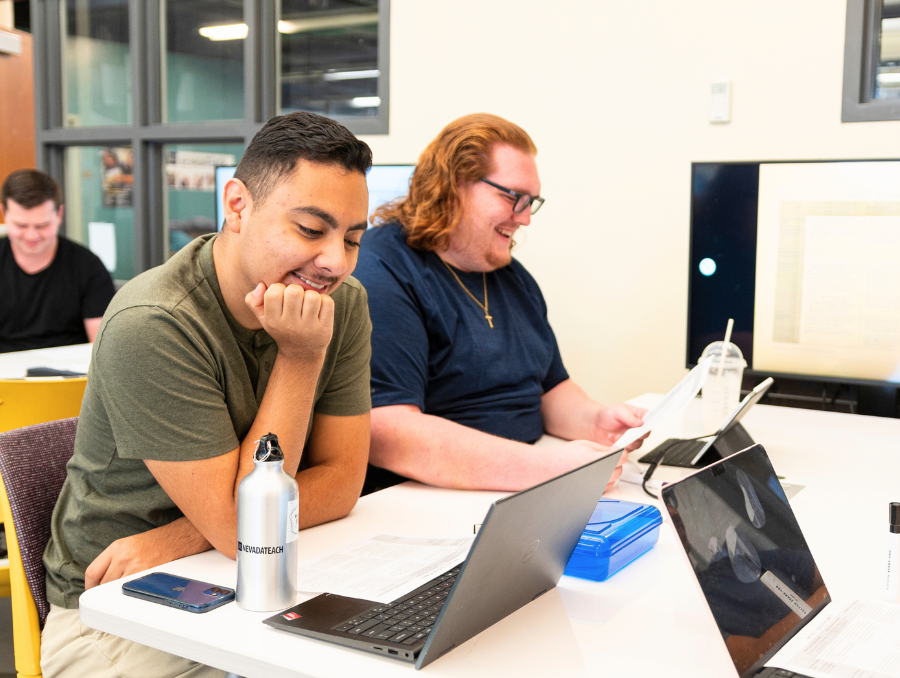 Two students in a classroom using computers.