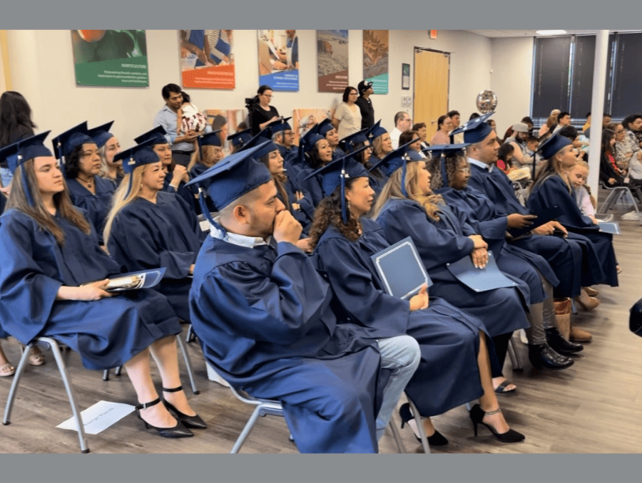 People in gowns and caps seated in a room.