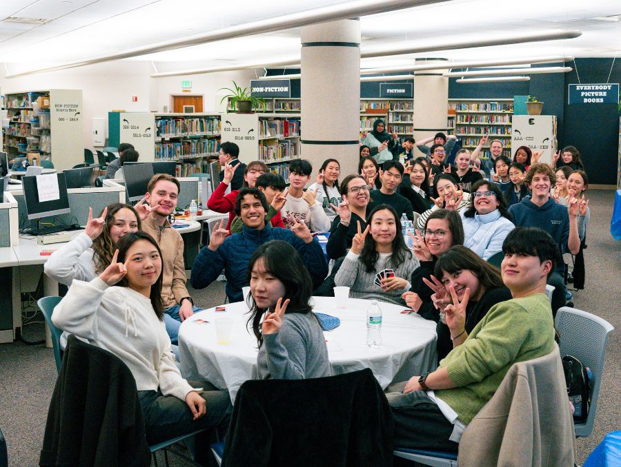 American and South Korean students at a social event, sitting at tables.
