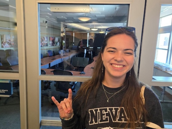 Miriam Dayton smiling and holding up a Wolf Pack Hand Sign.