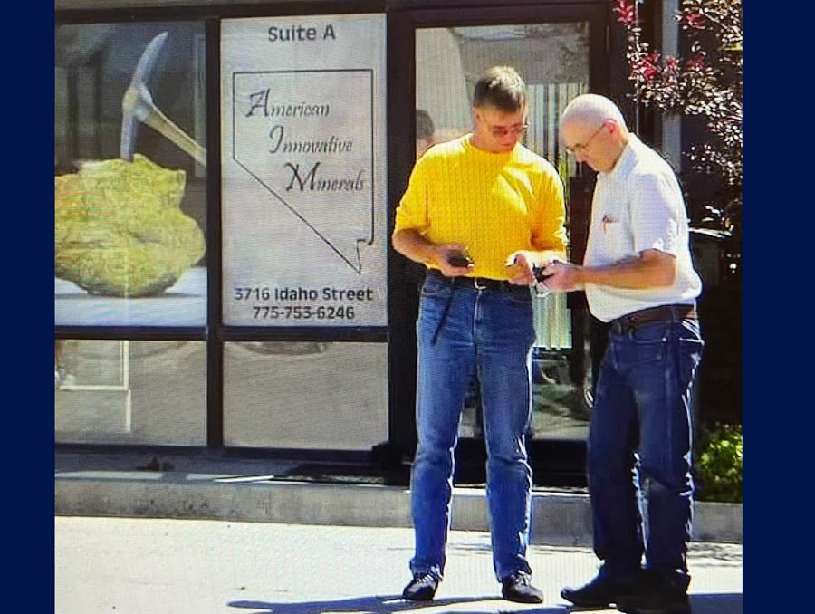 Two people stand outside a building with the sign "American Innovative Materials."