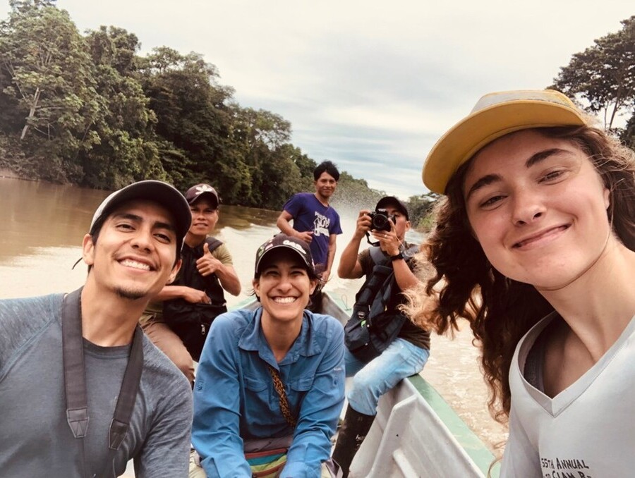 Smiling people sitting in a boat on a river.
