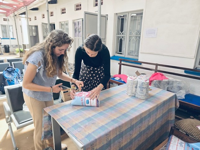 Two individuals examining a package on a table.
