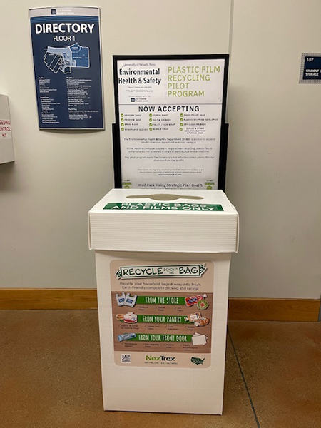 A tall box with signs behind and on the box explaining the plastic film recycling program at the University. 