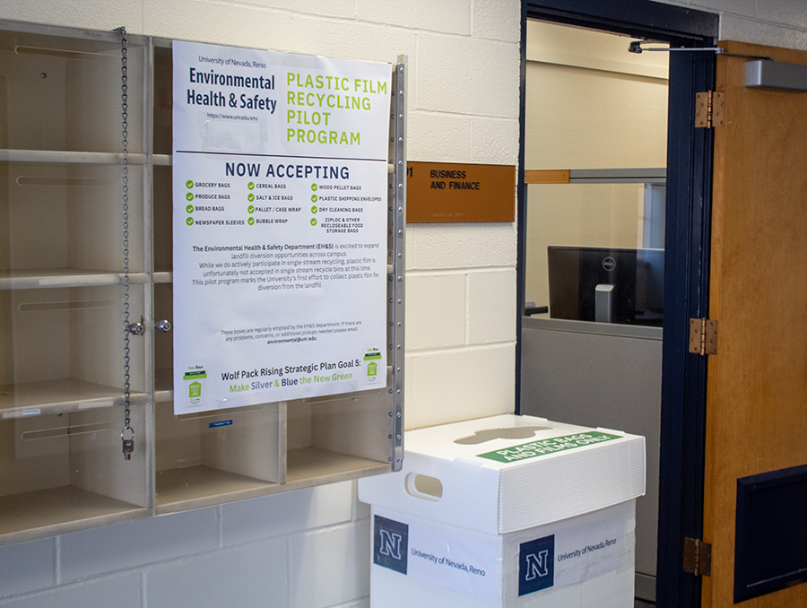 A recycling receptacle and sign in front of an open office door.
