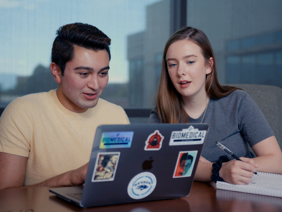 Two students looking at a computer together.
