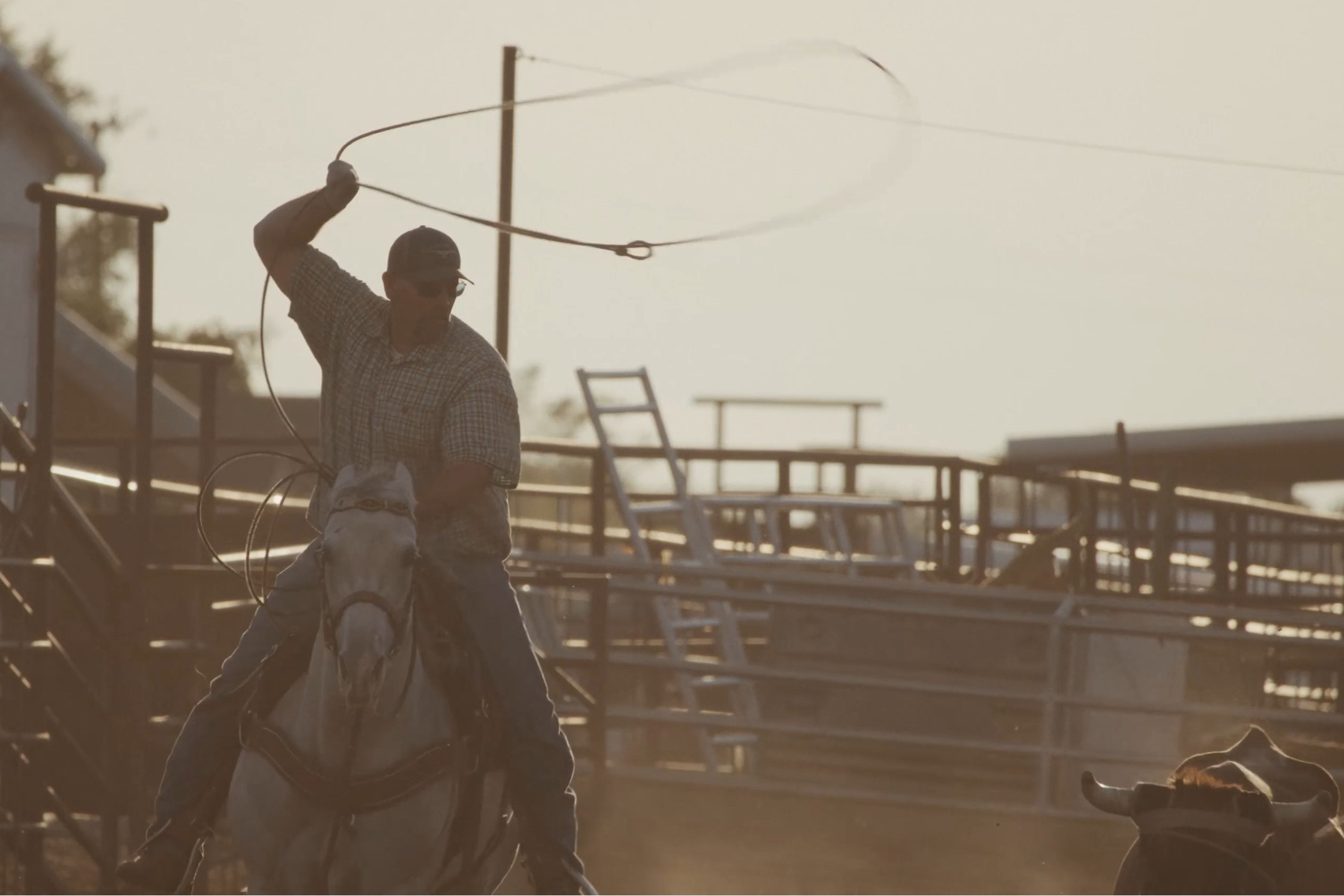 Two men, talking, walk toward the camera on a pier of a body of water.