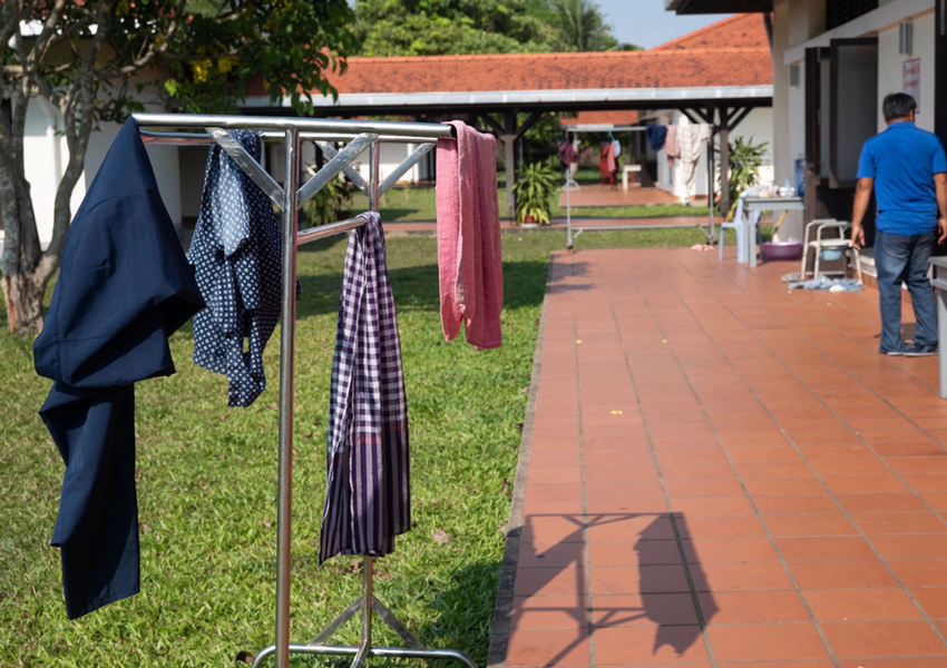 A drying rack with clothes and towels hangs on a grassy area outside the hospital.