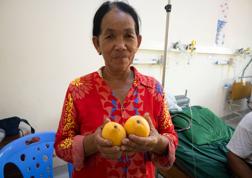 A woman holding up two yellow mangoes. 