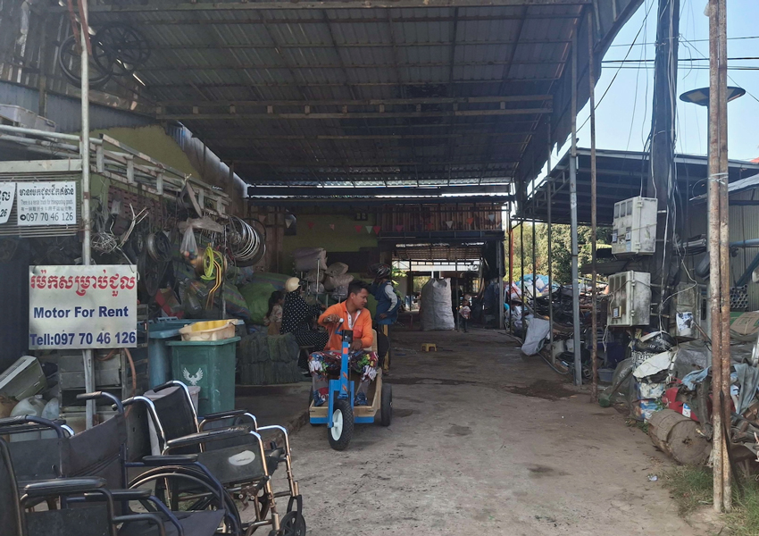 A large awning over a mechanic shop and a person riding a motor vehicle.