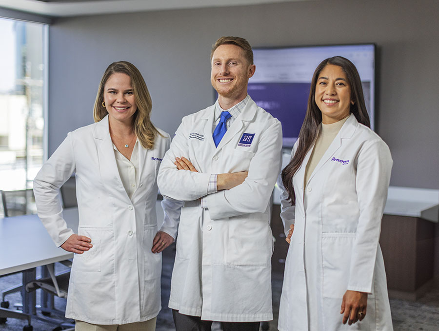 Three physicians in white coats standing in a conference room.