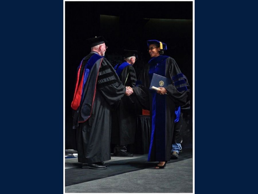 Dominique Daniel shakes hands with the provost during her degree conferral ceremony.
