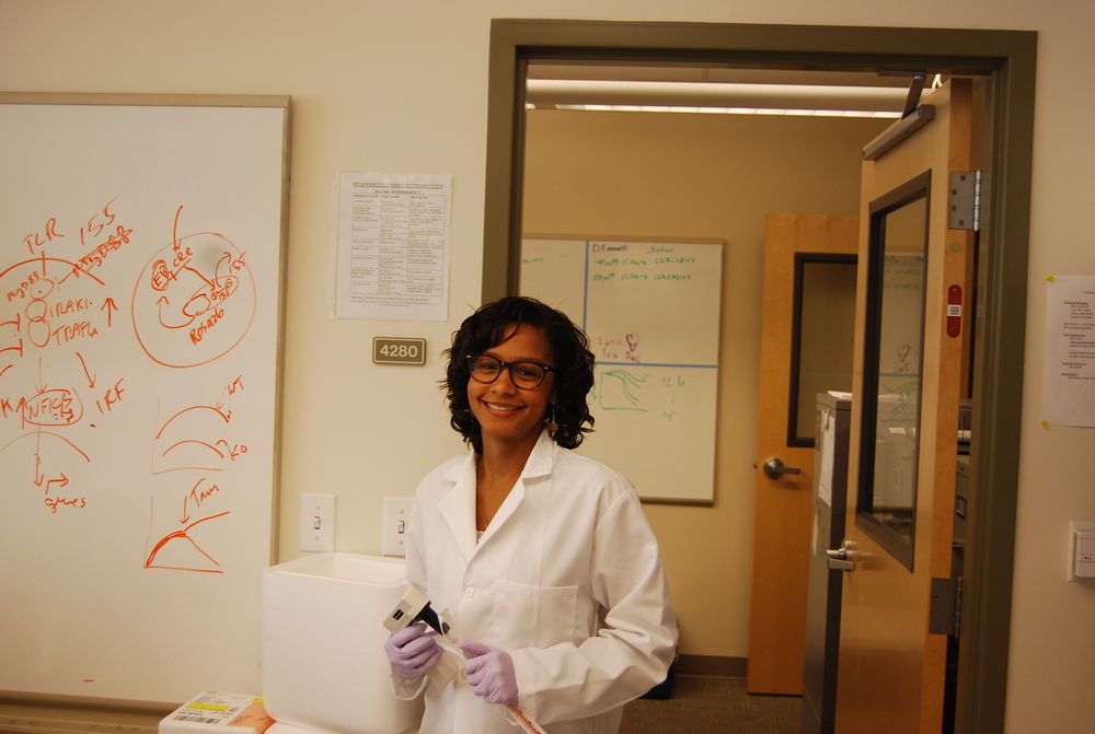Dominique working in a lab, smiling.