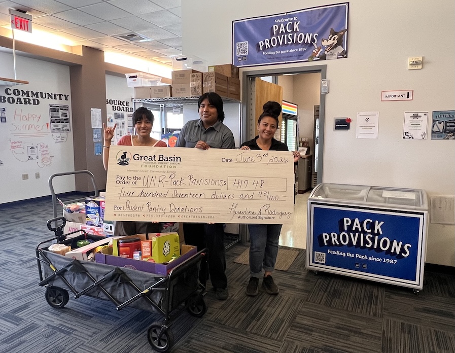Three people standing near a Pack Provisions sign, smiling and holding a large check for $417.78, made payable by Great Basin Federal Credit Union, to Pack Provisions.