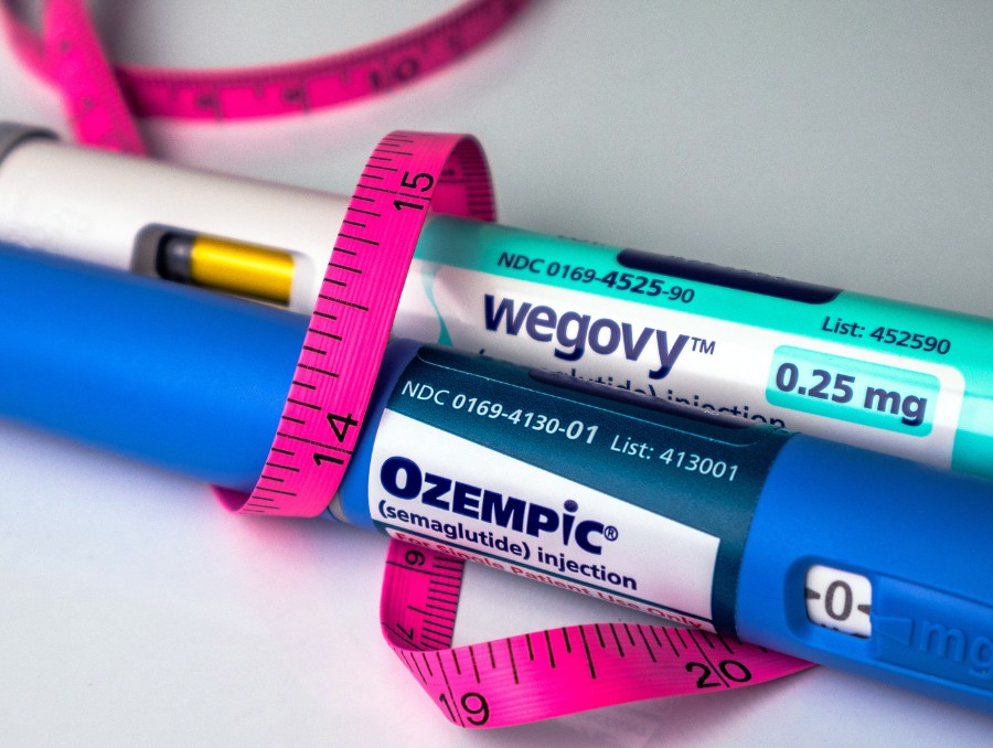 Ozempic and Wegovy with a tape measure wrapped around.