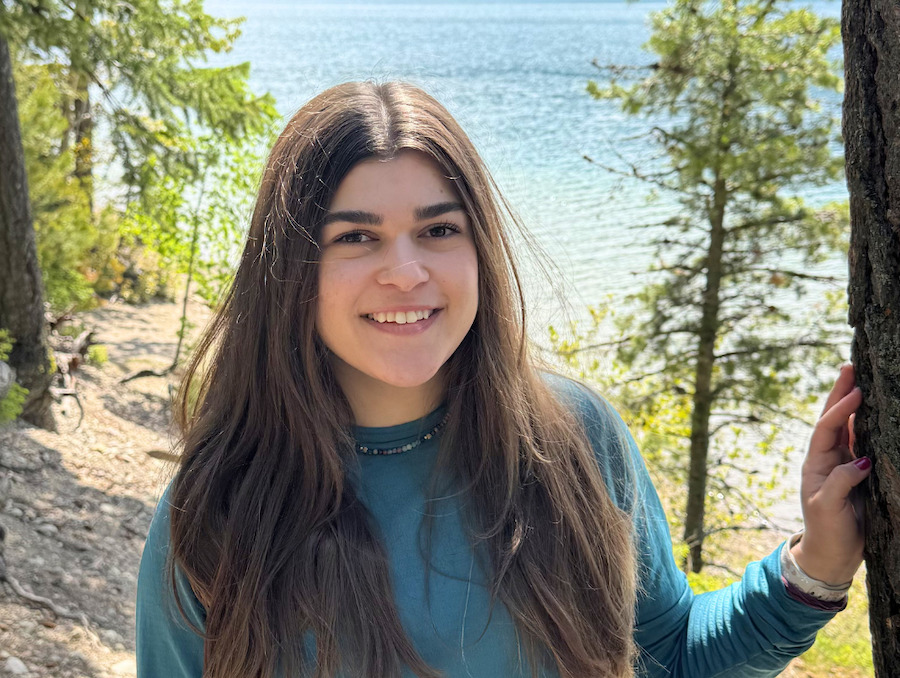 Student Kaden Ackerson poses in front of a lake and trees.