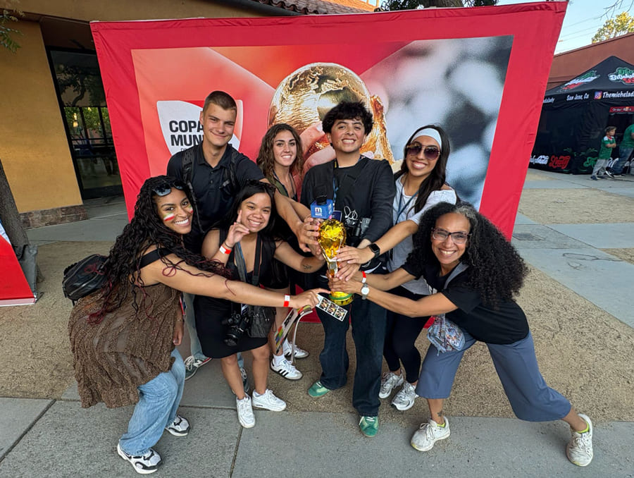 A group of students pose with a World Cup replica trophy. 