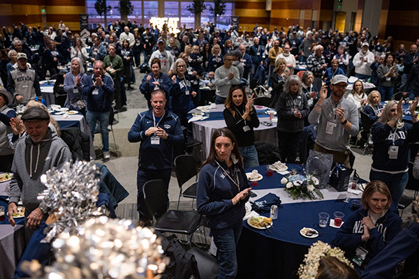 Attendees at the President&rsquo;s Tailgate stand and applaud during a University of Nevada event, filling a large banquet hall with round tables and university-themed d&eacute;cor.