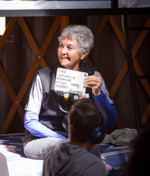 Angie DiPrinzio in a Yurt holding up "I Am" statement words on a small white board.