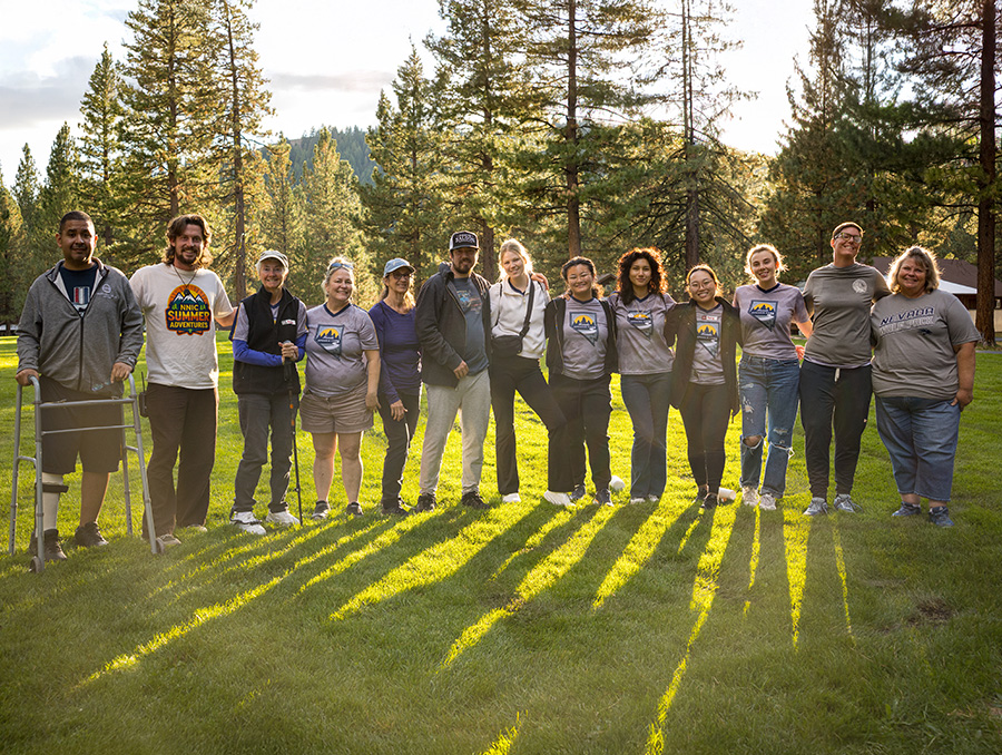 Attendees of the 2025 Nevada Aphasia Camp stand together in a grassy field.