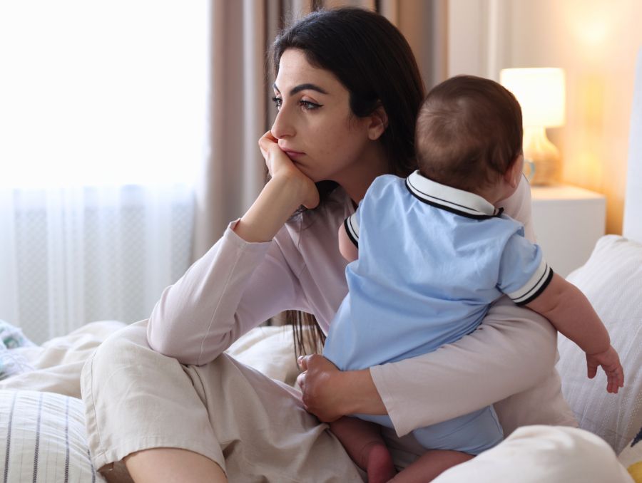 A mother looks sad holding her baby.