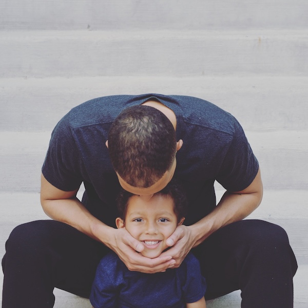 Ford holding his son Carter on a staircase, kissing the top of Carter's head.
