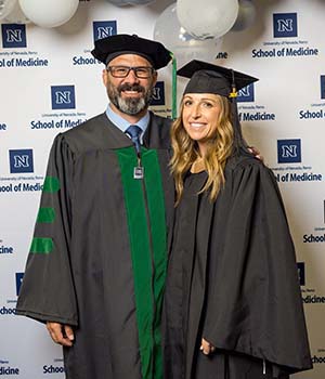 David Tingle and his wife posing together wearing a graduation cap and gown.