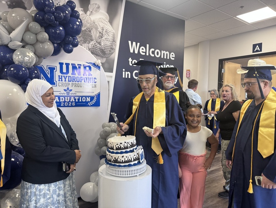 Dr. Gordon poses by a decorated cake during the graduation ceremony.