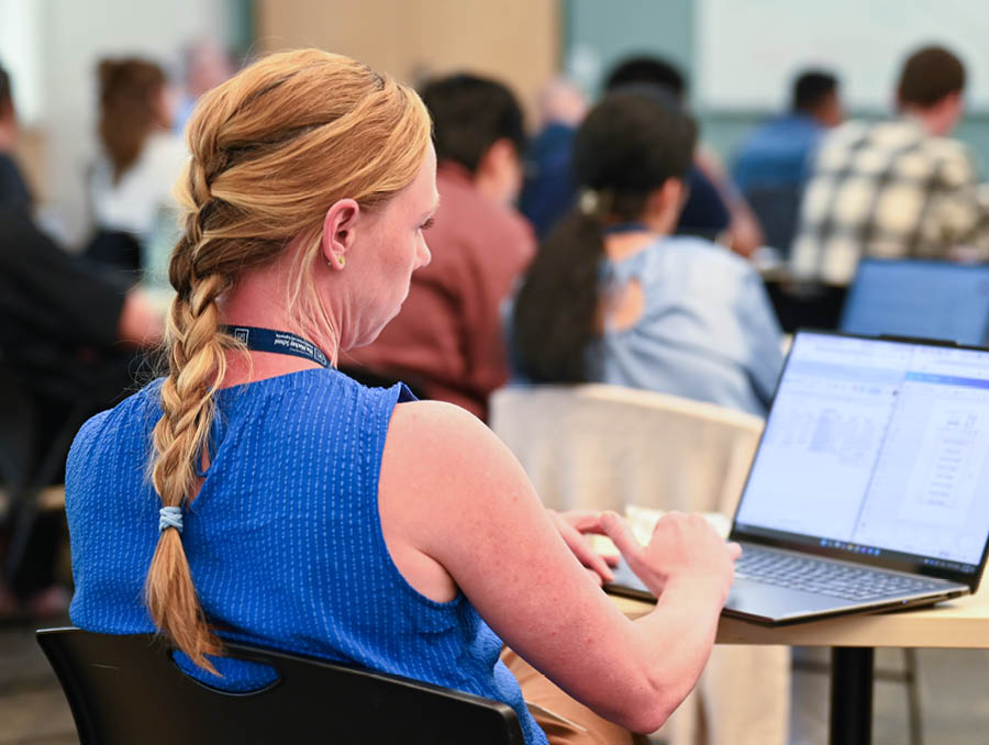 A woman types on her computer in a classroom.