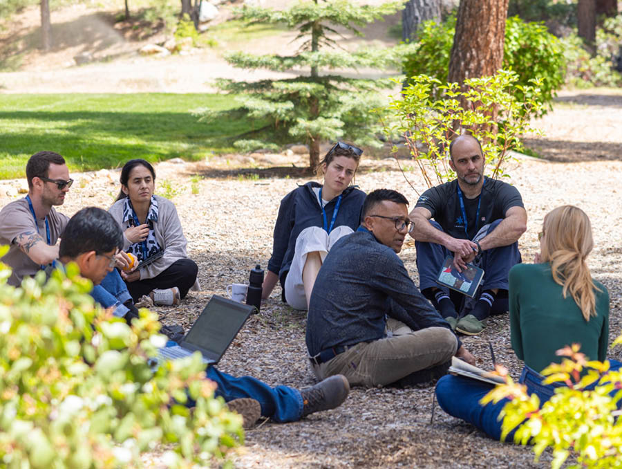 Workshop participants sit outside discussing with each other.