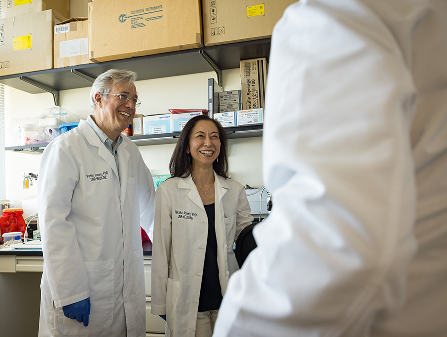 Peter and Takako Jones in the lab talking to another researcher.