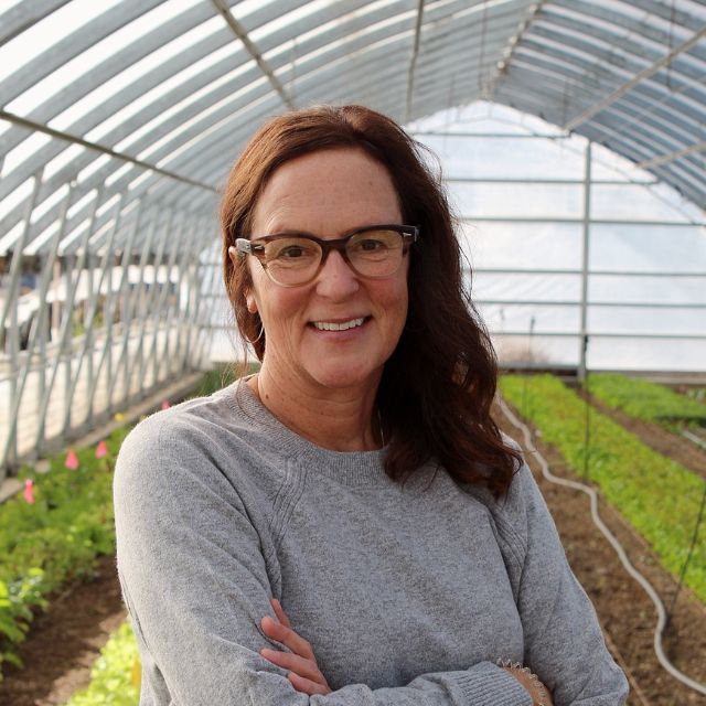 Jill Moe posing in a hoop house. 