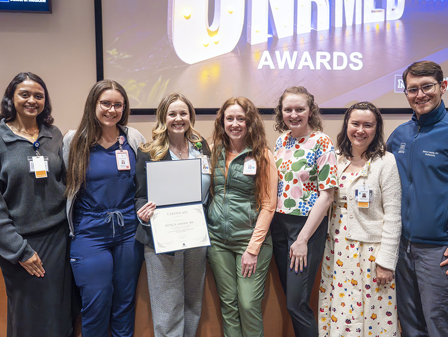 Pediatrics residents supporting their peer, Natalie Osborn,, M.D., holding her first place certificate at the Goodman Resident Research Competition.