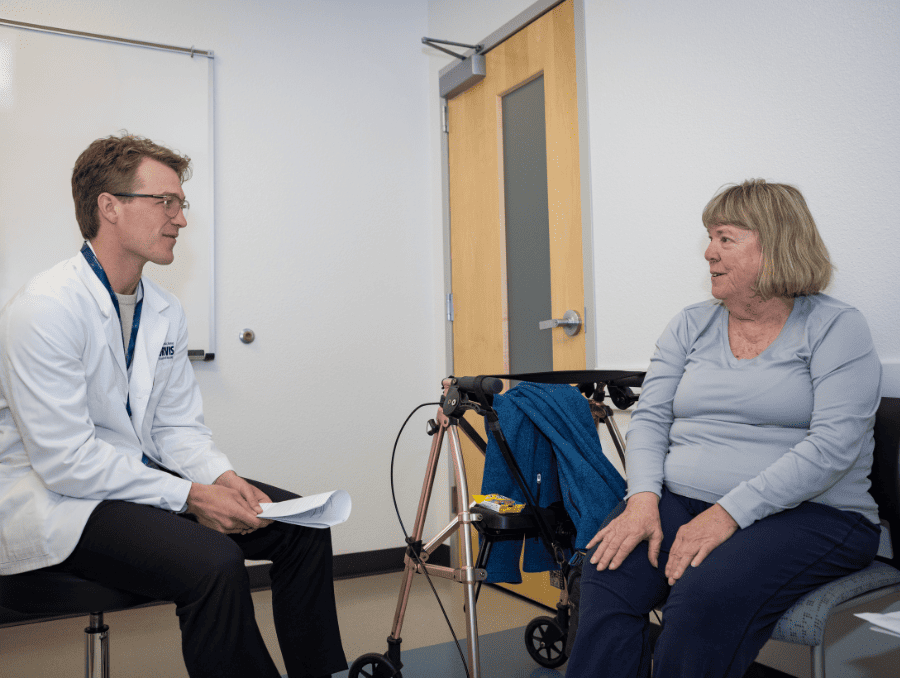 A medical student meeting with an older woman in a clinic setting.