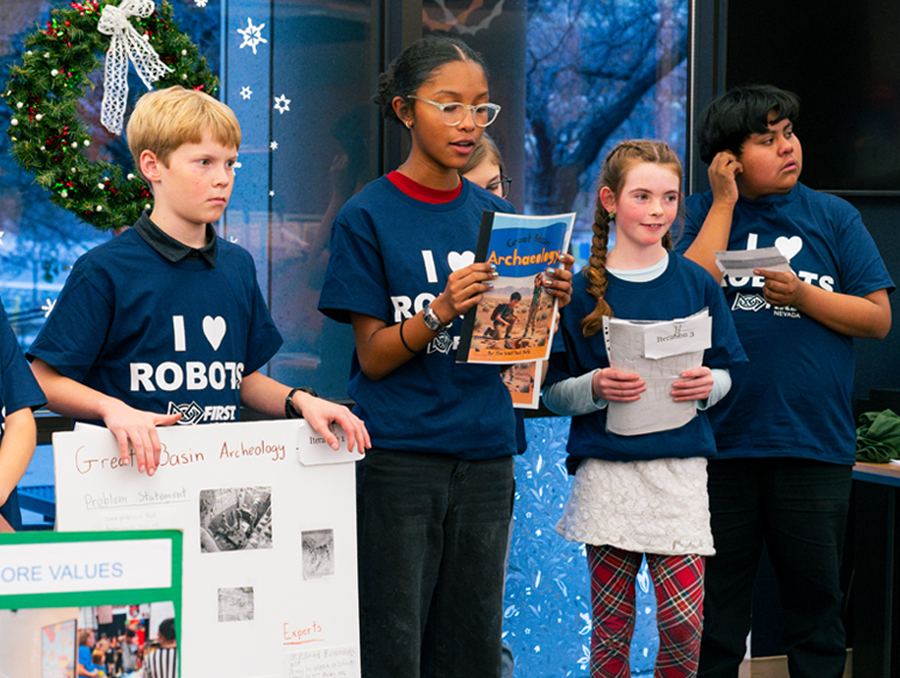 Students holding notes and posters presenting their research project.