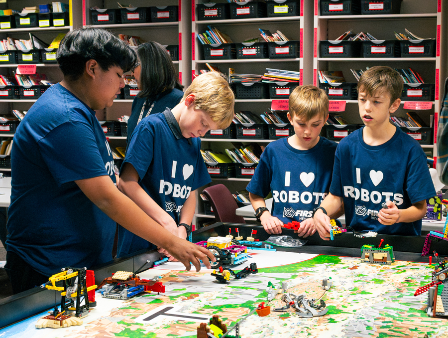 Students stand around a table with robots