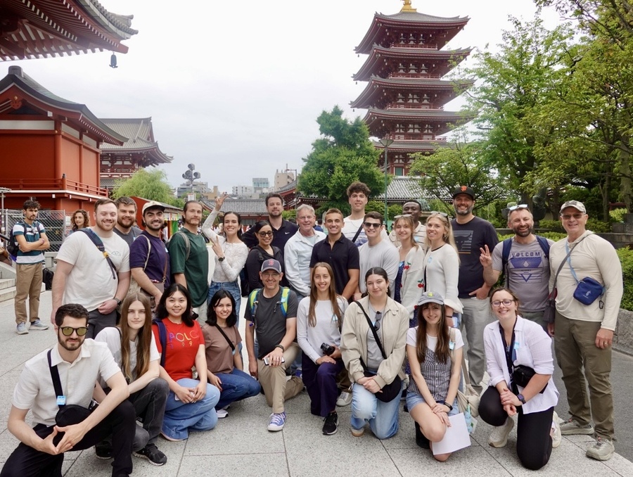 A group of University of Nevada, Reno students and faculty pose together in Tokyo with a multi-story pagoda-style temple and traditional buildings in the background.