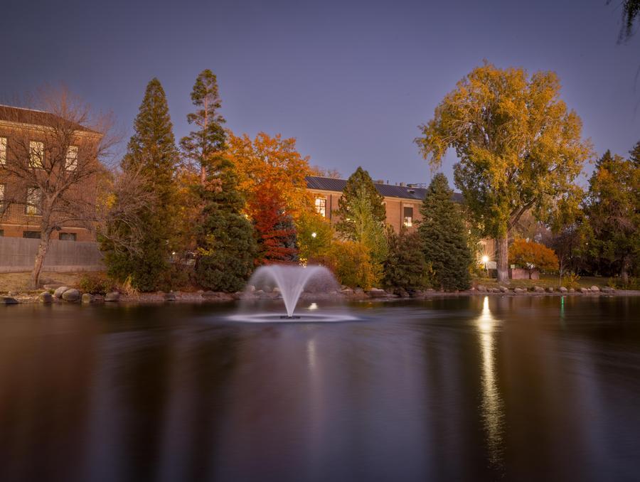 Manzanita lake with a fountain going off in the middle around dusk on campus.