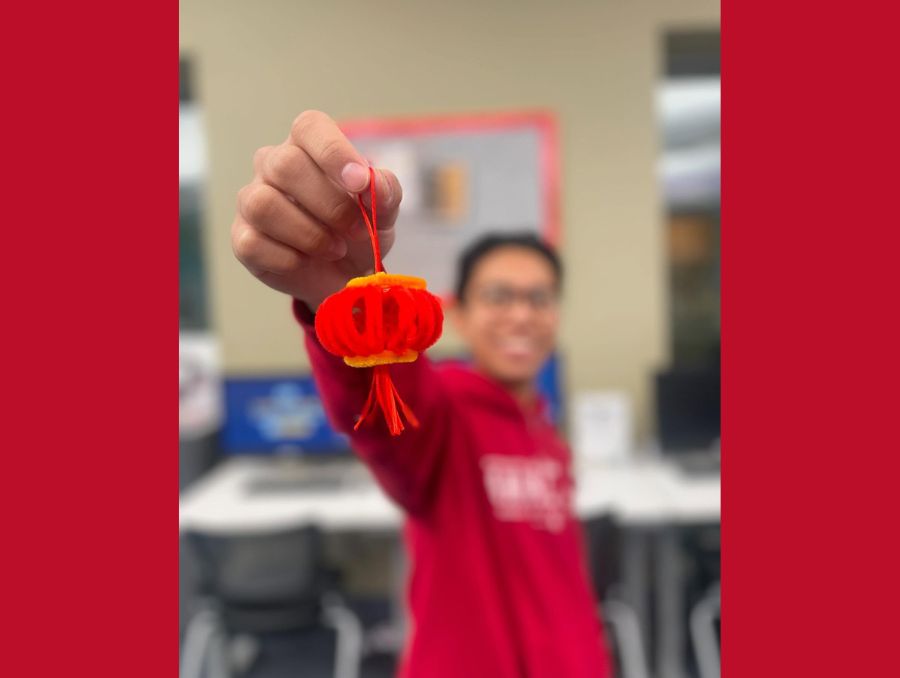 A student holds up a small, red paper lantern during Lunar New Year.