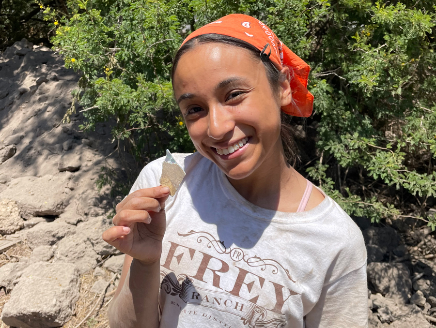 Lupe Alvarez on an archeology excursion holding up a material she found.