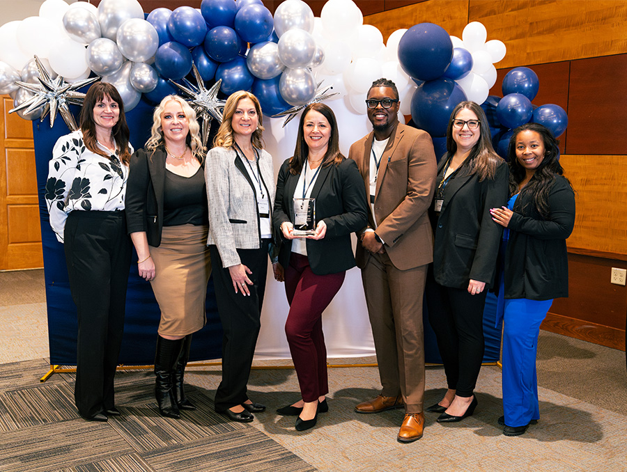 The MTSS conference attendees posing in front of a blue, white and silver balloon arch.