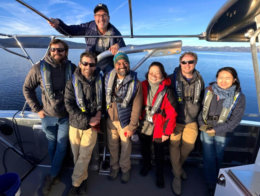 A group of scientists from the workshops stand on a boat out on Lake Tahoe.